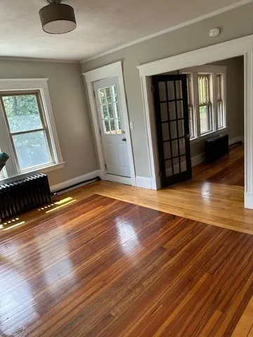 a view of an empty room with wooden floor and a window