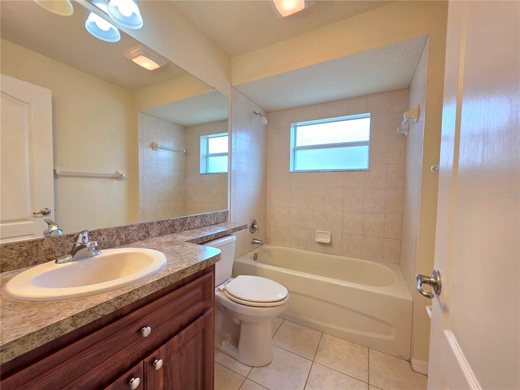 4284 High Ridge Avenue Spring Hill, FL 34609 - Photo 31 of 40 a bathroom with a granite countertop sink a toilet a mirror and shower