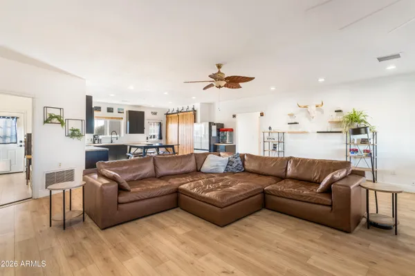 a view of living room kitchen with stainless steel appliances kitchen island granite countertop a couch and a view of living room