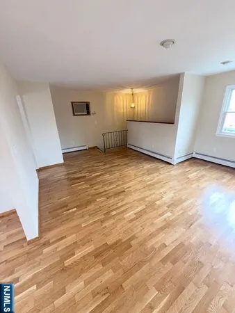 a view of an empty room with wooden floor and windows