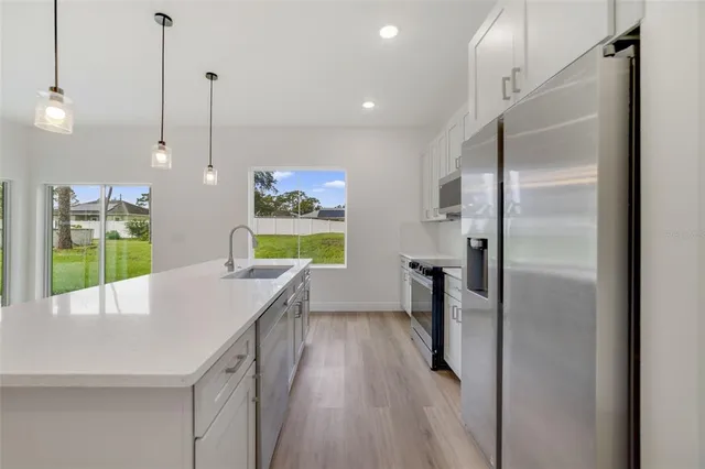 a kitchen with a sink a refrigerator and a wooden floor