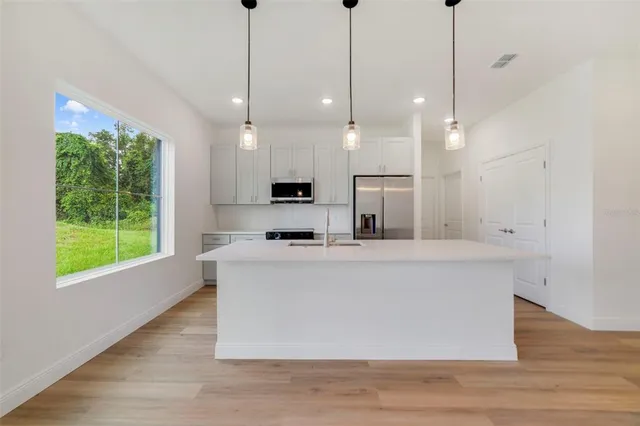 a view of kitchen with stainless steel appliances granite countertop a sink a window and a wooden floor