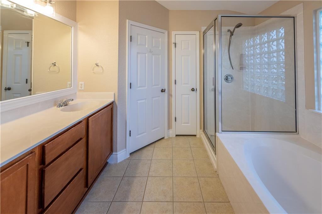 12017 Springs Head Loop Austin, TX 78717 - Photo 15 of 25 A well-lit bathroom with a glass-enclosed shower and a spacious vanity.