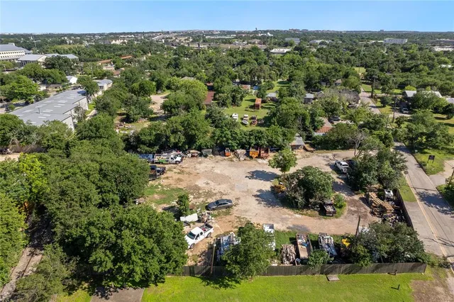 an aerial view of a residential houses with outdoor space and trees all around