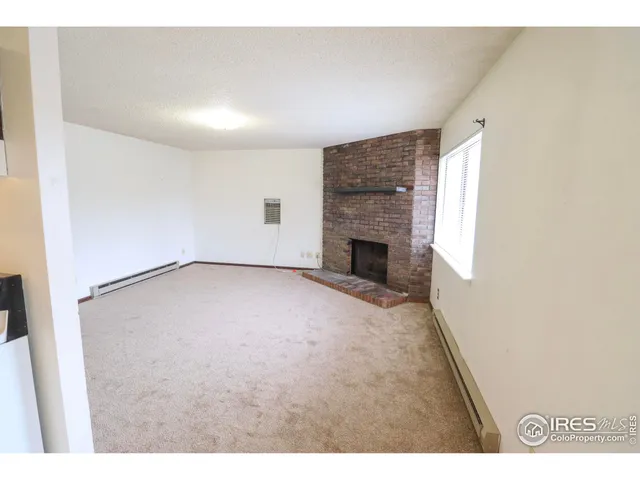 a view of an empty room with a fireplace and a window