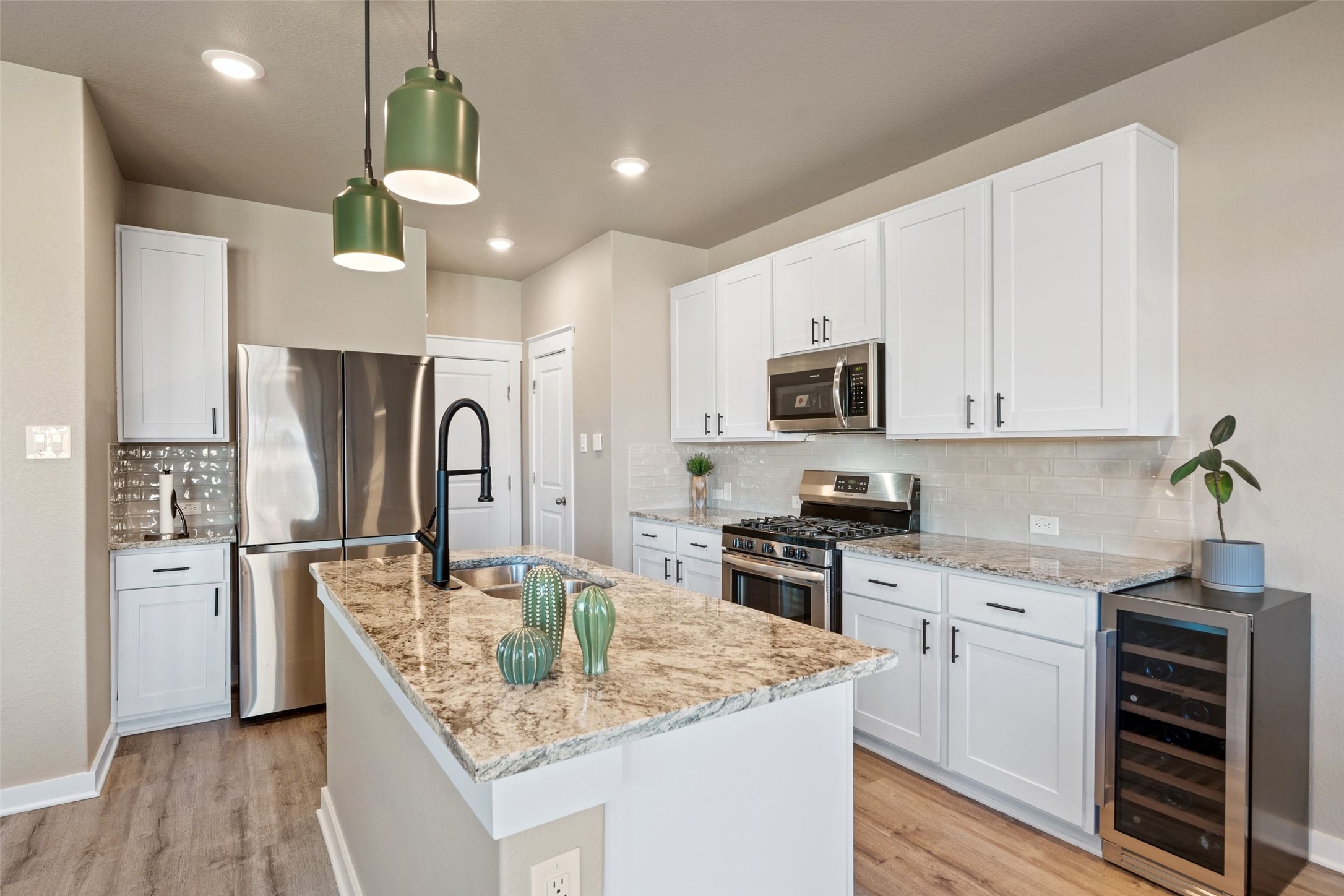 2251 Rocoso Trail Leander, TX 78641 - Photo 5 of 24 a kitchen with kitchen island granite countertop a stove a sink a refrigerator and white cabinets with wooden floor