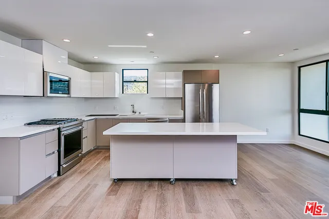 a kitchen with stainless steel appliances a sink wooden floor and stove