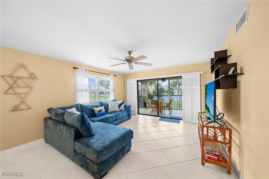 12581 Kelly Sands Way, Unit 518 Fort Myers, FL 33908 - Photo 8 of 33 a living room with furniture a flat screen tv and a floor to ceiling window