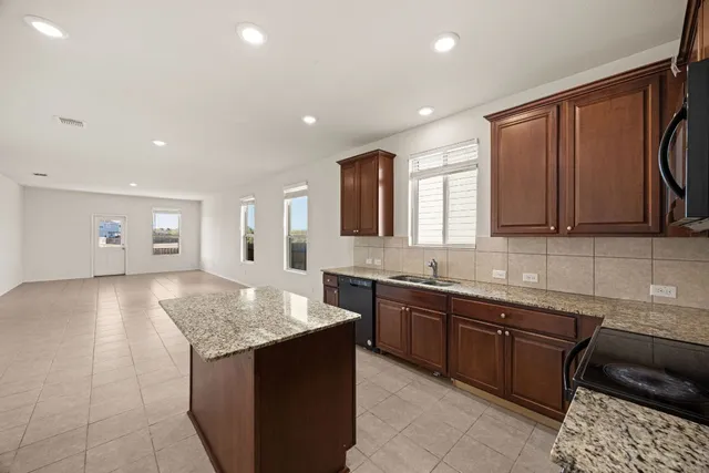 a kitchen with granite countertop sink stove and cabinets