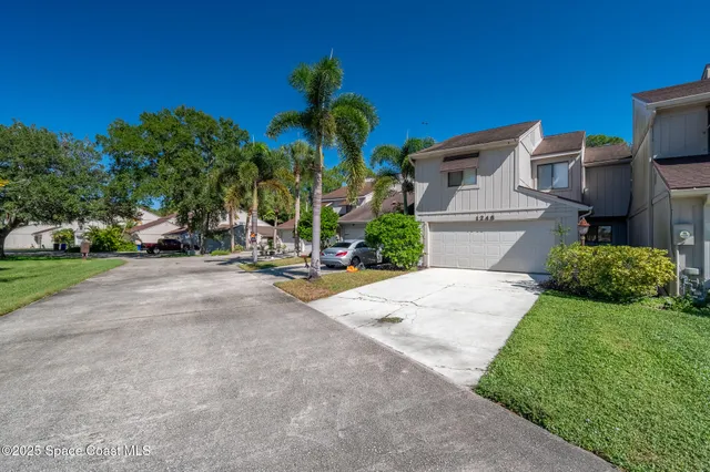 a view of a white house with a yard and potted plants