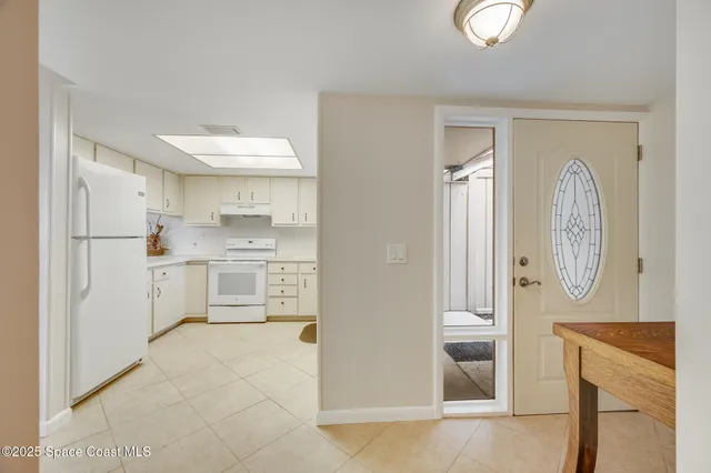 a kitchen with white cabinets and refrigerator