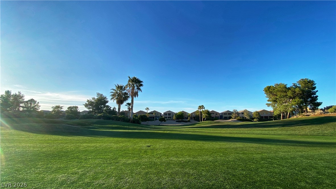 489 Foster Springs Road Las Vegas, NV 89148 - Photo 20 of 30 Lush green fairways extend toward residences under a brilliant sky, offering serene golf course living.