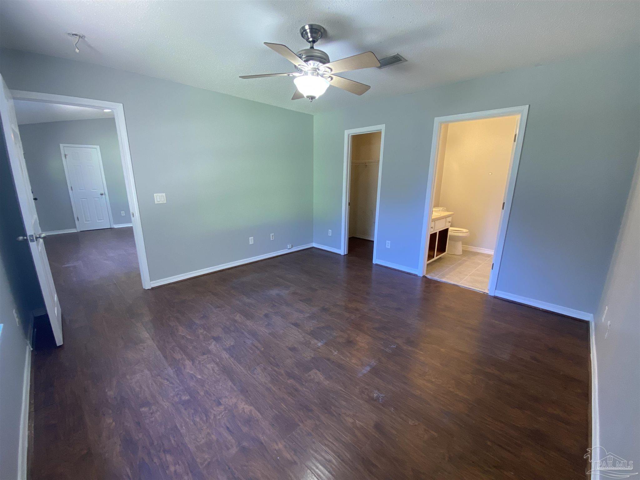 5493 Riviera Drive Milton, FL 32583 - Photo 11 of 21 an empty room with wooden floor and a ceiling fan
