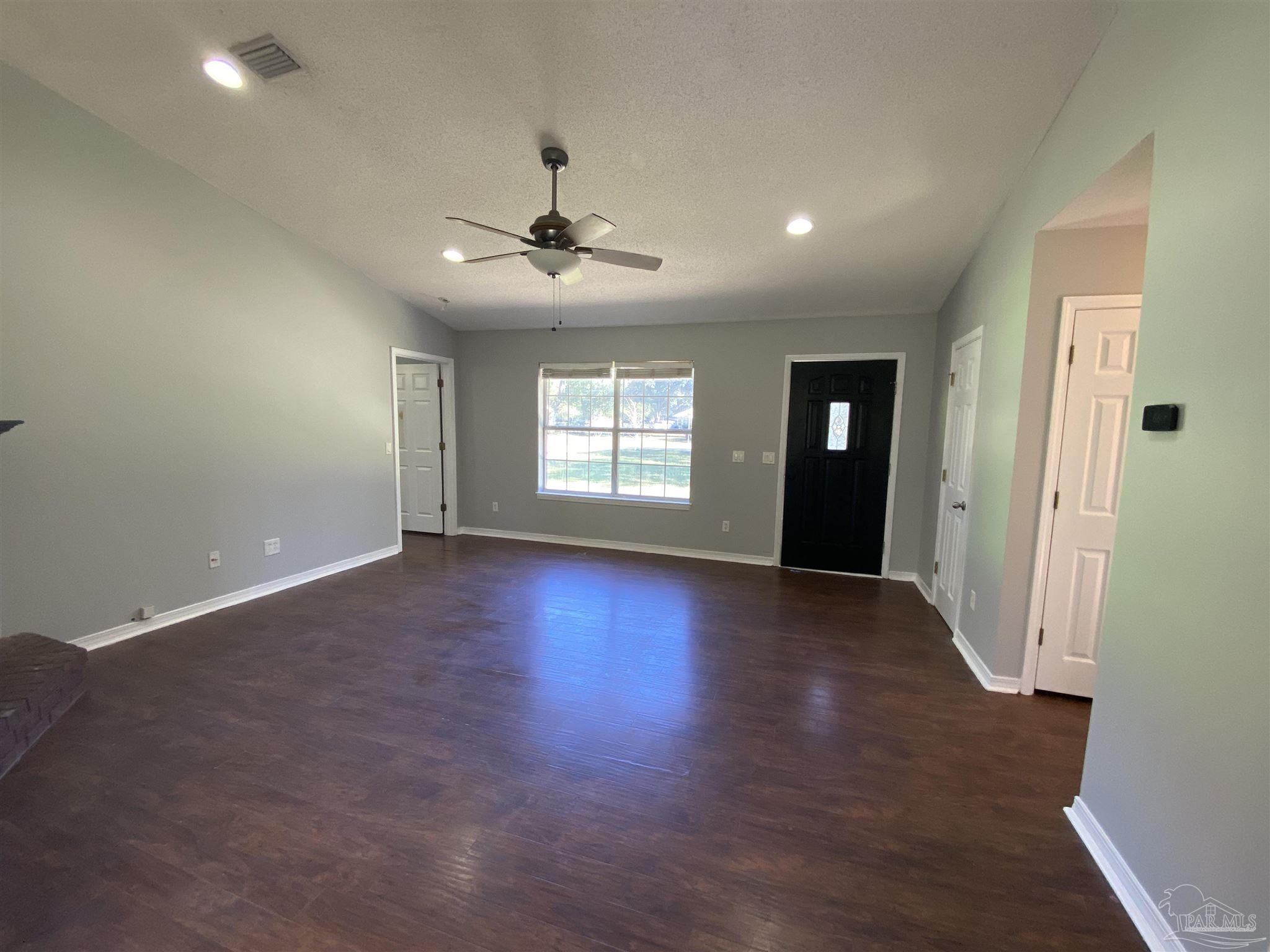 5493 Riviera Drive Milton, FL 32583 - Photo 5 of 21 a view of empty room with wooden floor and fan
