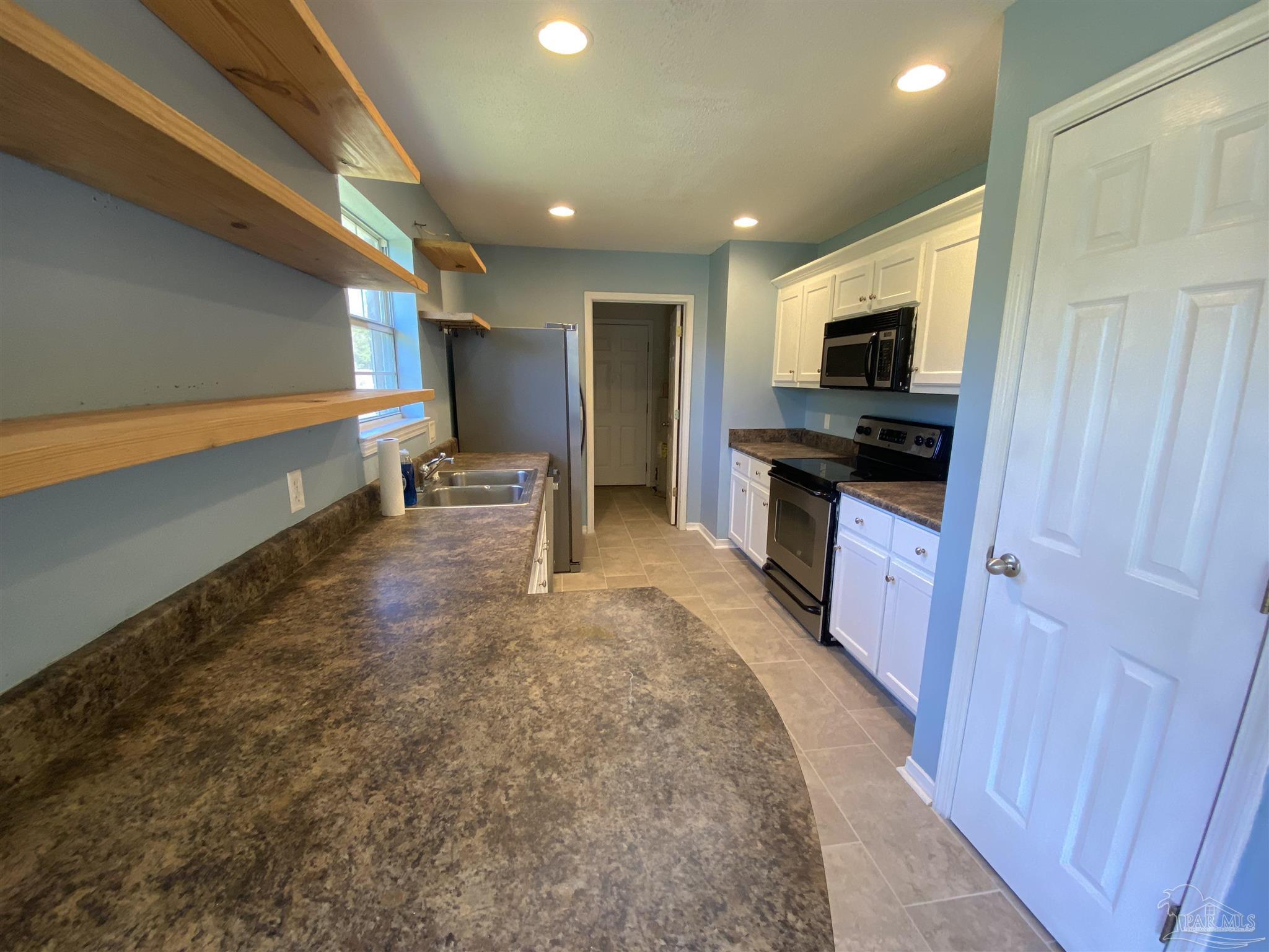 5493 Riviera Drive Milton, FL 32583 - Photo 8 of 21 a kitchen with stainless steel appliances granite countertop a refrigerator and a stove top oven