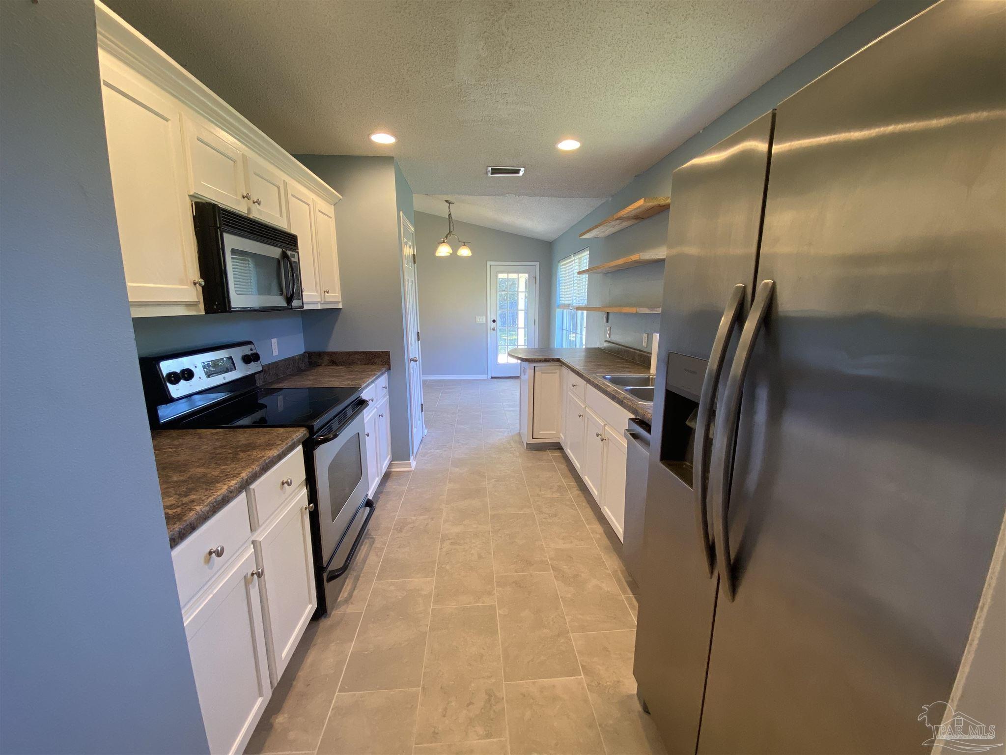 5493 Riviera Drive Milton, FL 32583 - Photo 9 of 21 a kitchen with stainless steel appliances granite countertop a refrigerator a stove and a sink with wooden floor