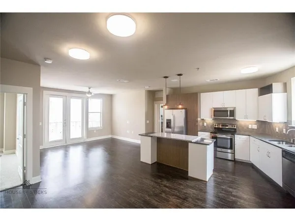 a kitchen with stainless steel appliances granite countertop a stove top oven a sink dishwasher and white cabinets with wooden floor