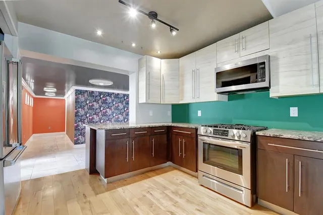 a view of a hallway with wooden floor and a bathroom