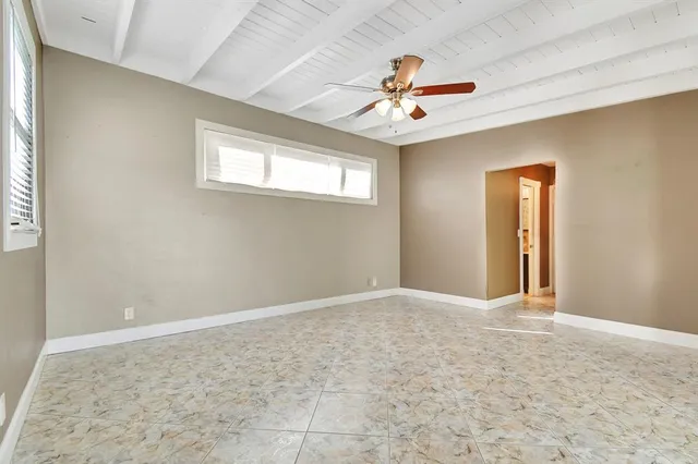 an empty room with ceiling fan and windows