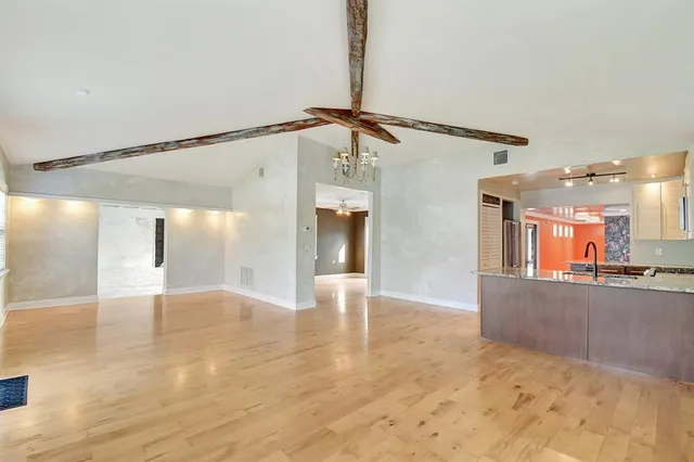 a view of a hallway with wooden floor and a living room