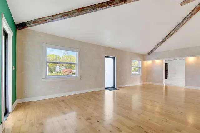 a view of an empty room with window and wooden floor