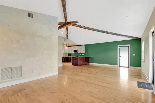 a view of a room with wooden floor ceiling fan and windows