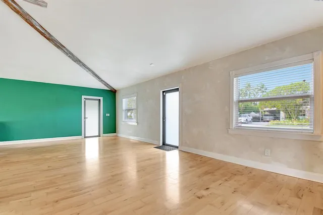 a view of an empty room with window and wooden floor