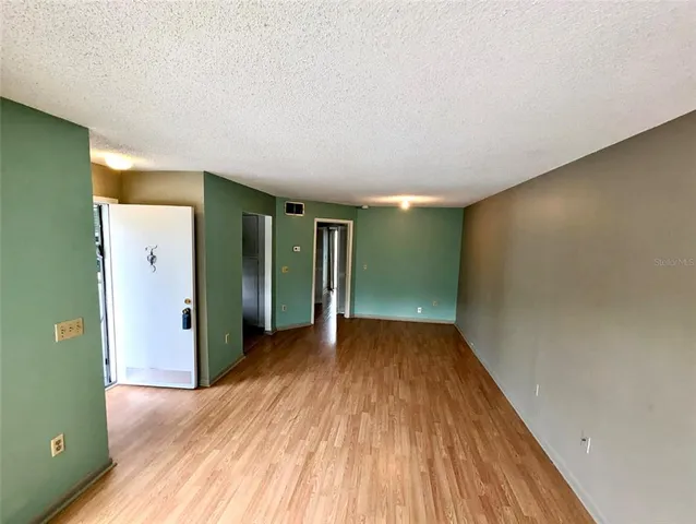 a view of an empty room with wooden floor and closet
