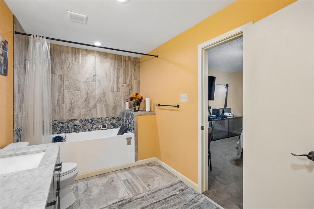2617 Quail Ridge Irving, TX 75060 - Photo 8 of 17 Master bathroom featuring a built-in tub with tile surround, a built-in vanity with a rectangular basin, and large-format tile flooring