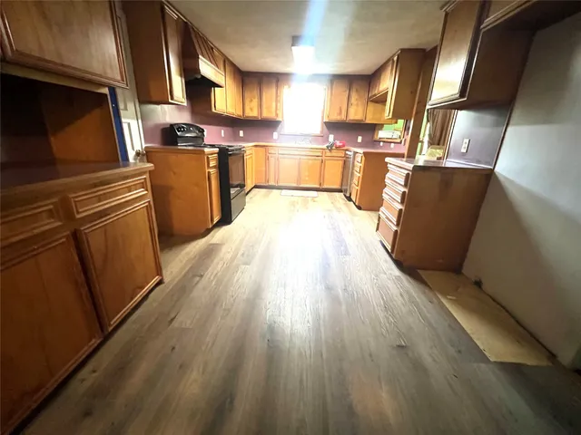 a kitchen with stainless steel appliances wooden floors and wooden cabinets