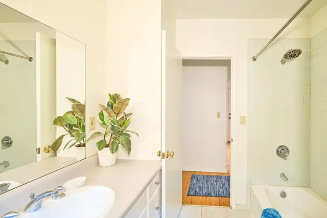 a bathroom with a granite countertop sink a mirror a bathtub and shower