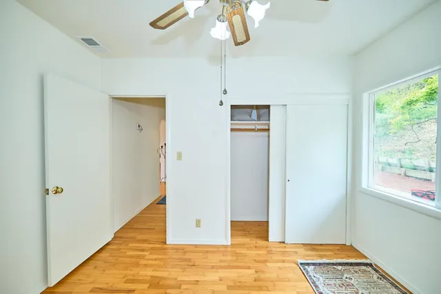 a view of a room with wooden floor fan and window