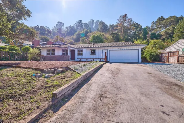 a view of a house with a yard and a large tree