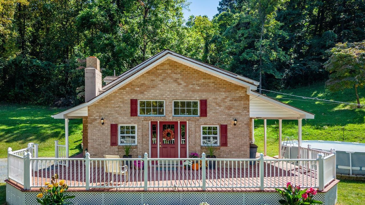 279 Helms Road Stanley, VA 22851 - Photo 2 of 64 a view of a brick house with a small yard plants and large trees
