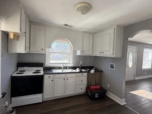 a kitchen with kitchen island granite countertop a sink cabinets and wooden floor
