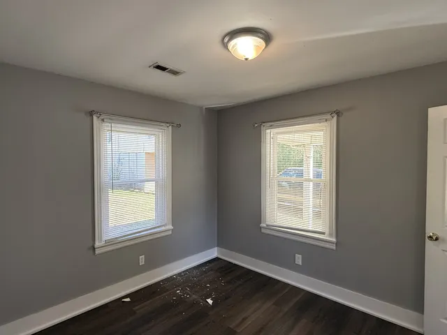 an empty room with wooden floor and windows