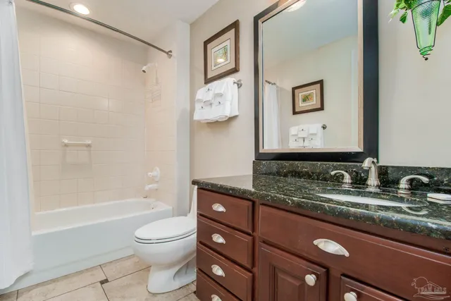 a bathroom with a granite countertop sink toilet and painting on the wall