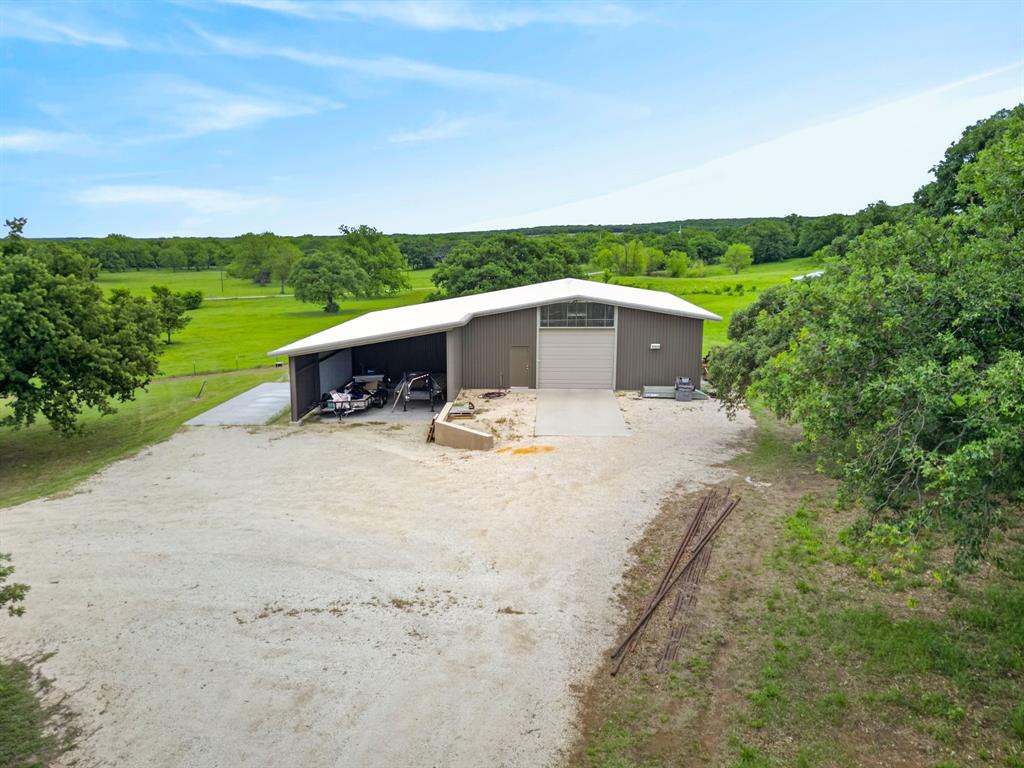 1080 North Greenbrier Road Nocona, TX 76255 - Photo 32 of 40 Metal outbuilding featuring a white sloped roof and an attached open-sided lean-to