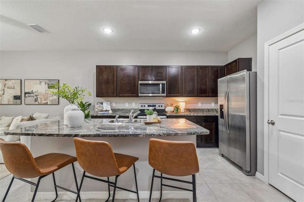 33083 Frosted Clover Way Wesley Chapel, FL 33545 - Photo 28 of 70 a kitchen with stainless steel appliances granite countertop a refrigerator and a stove top oven