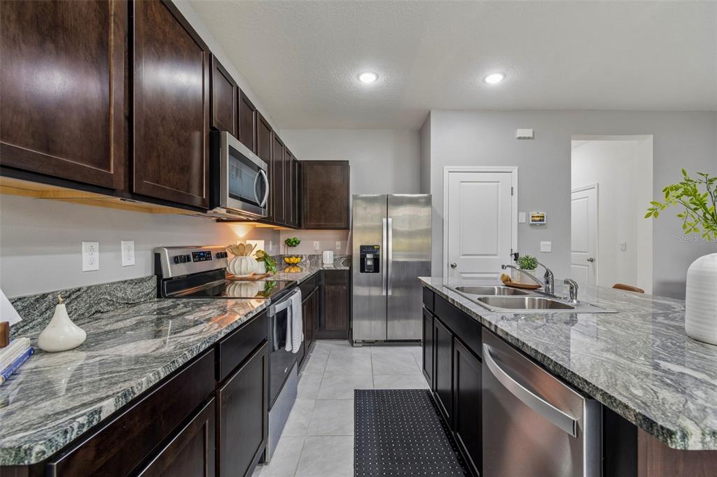 33083 Frosted Clover Way Wesley Chapel, FL 33545 - Photo 29 of 70 a kitchen with granite countertop stainless steel appliances and wooden cabinets