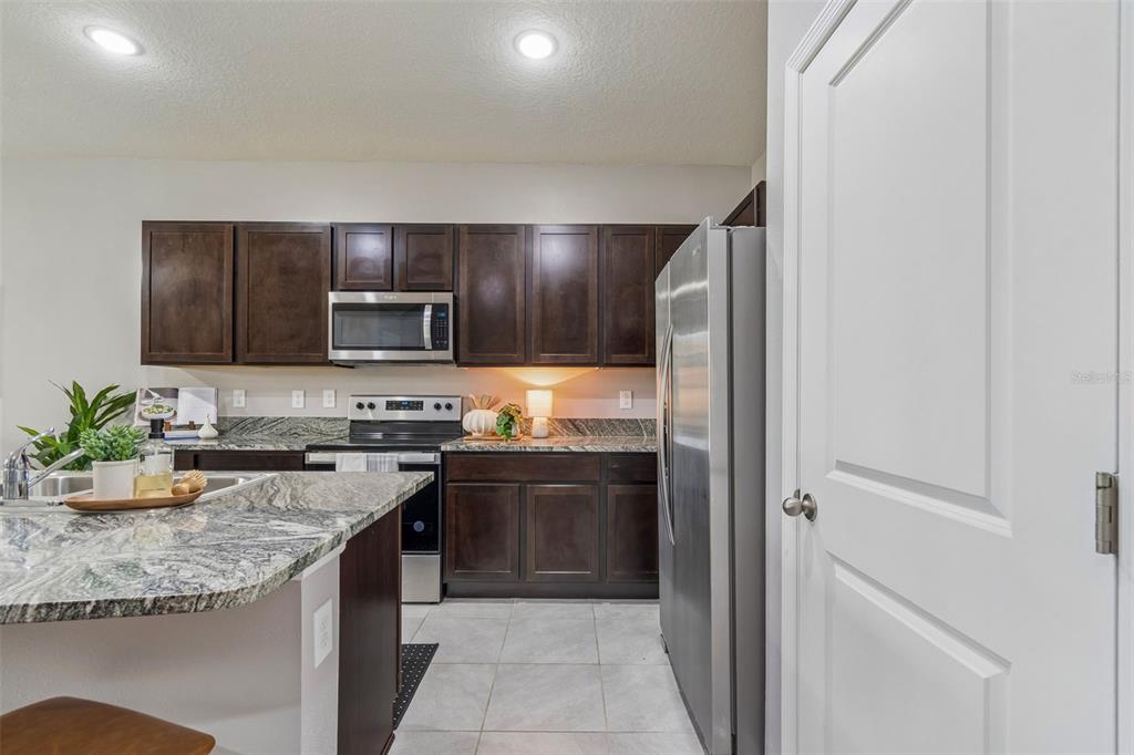 33083 Frosted Clover Way Wesley Chapel, FL 33545 - Photo 30 of 70 a kitchen with granite countertop stainless steel appliances and wooden cabinets