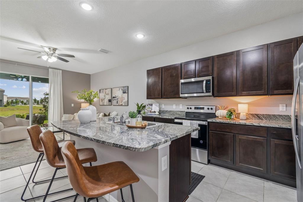 33083 Frosted Clover Way Wesley Chapel, FL 33545 - Photo 31 of 70 a kitchen with a stove a sink a microwave a dining table and chairs