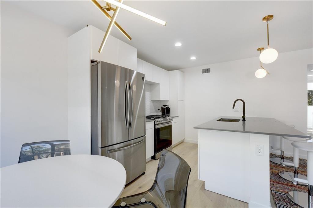 400 East 30th Street, Unit 204 Austin, TX 78705 - Photo 9 of 18 a kitchen with stainless steel appliances granite countertop a refrigerator a sink dishwasher a stove with white cabinets and wooden floor