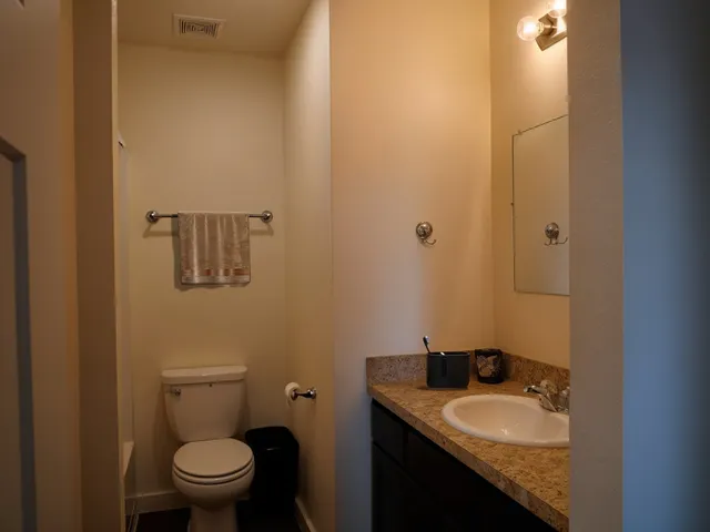 a bathroom with a granite countertop sink toilet and mirror