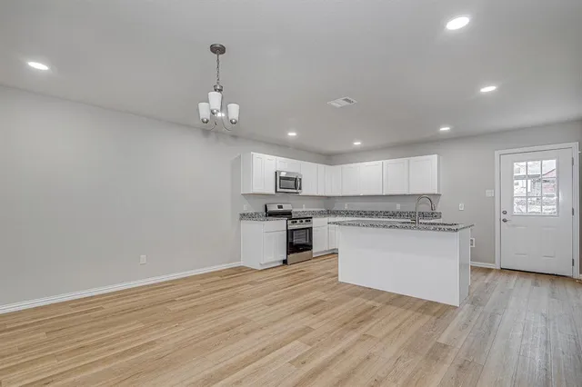 a kitchen with kitchen island a sink dishwasher stove and white cabinets with wooden floor