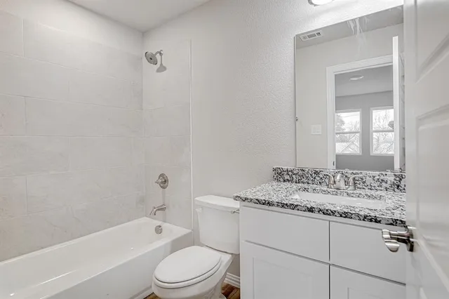 a bathroom with a granite countertop sink toilet mirror and bathtub