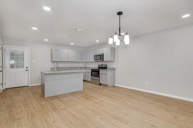 a view of kitchen with granite countertop cabinets and refrigerator