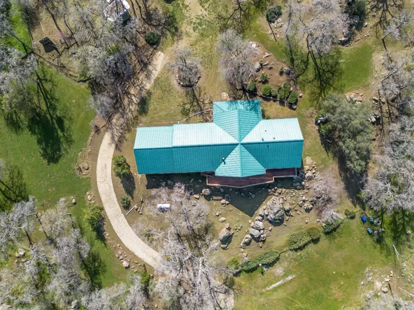 an aerial view of a house with swimming pool and large trees