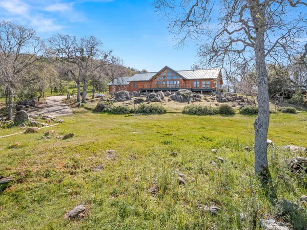 a view of a large pool with lawn chairs under an umbrella