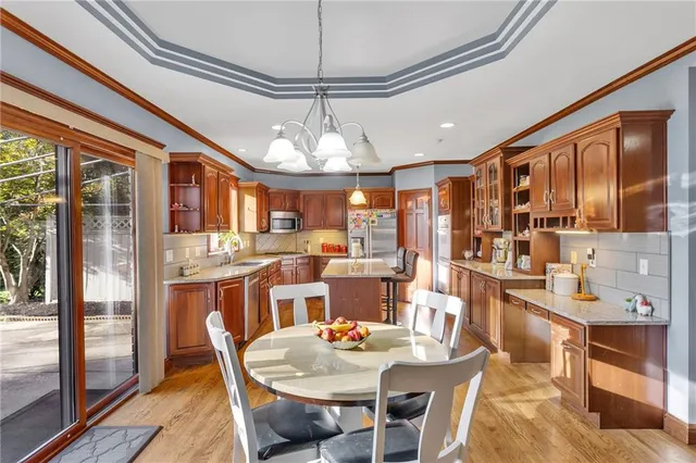 a dining area with stainless steel appliances granite countertop furniture and a chandelier